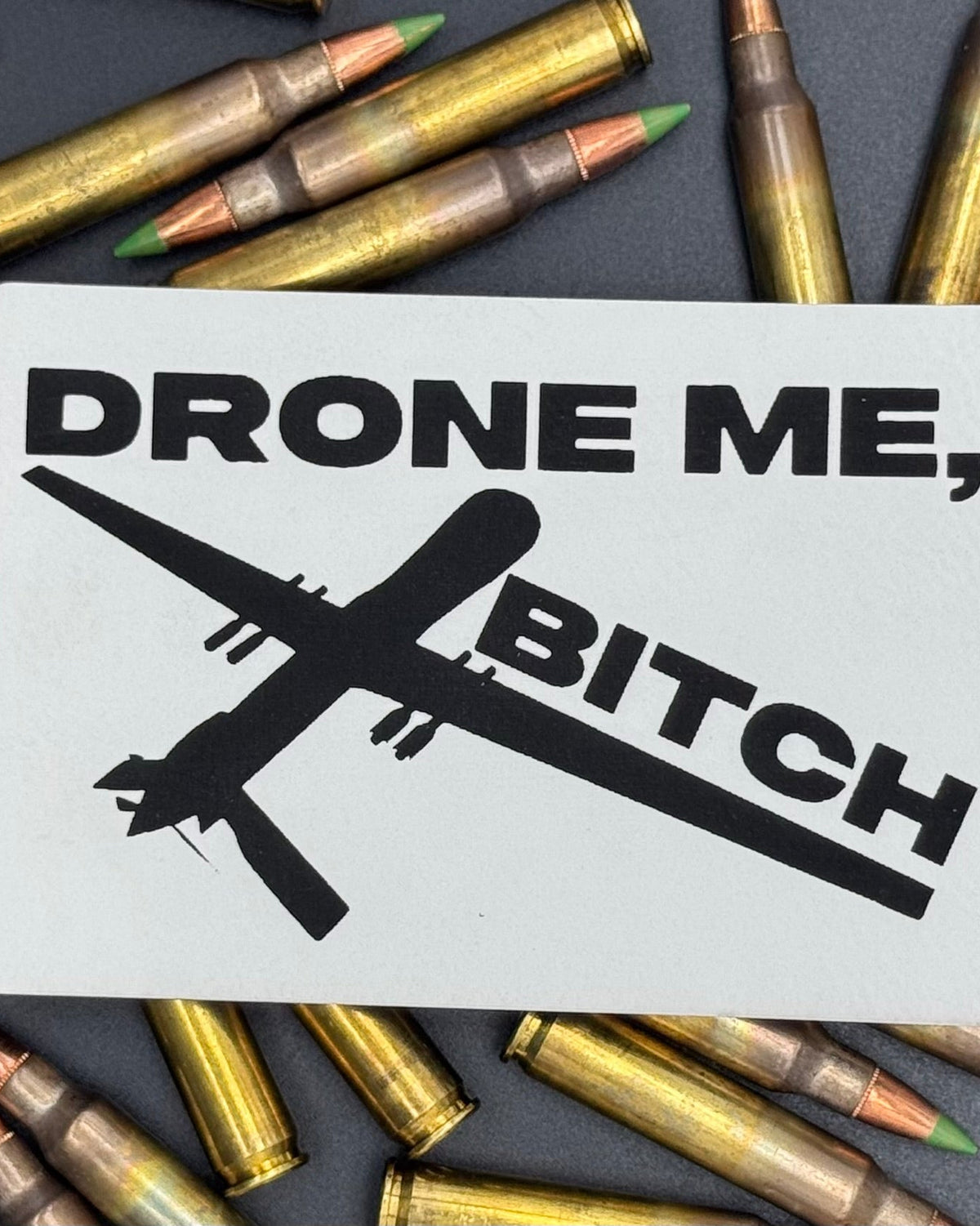 A white leatherette patch of a reaper drone and the text 'Drone Me, Bitch' on a bed of ammo