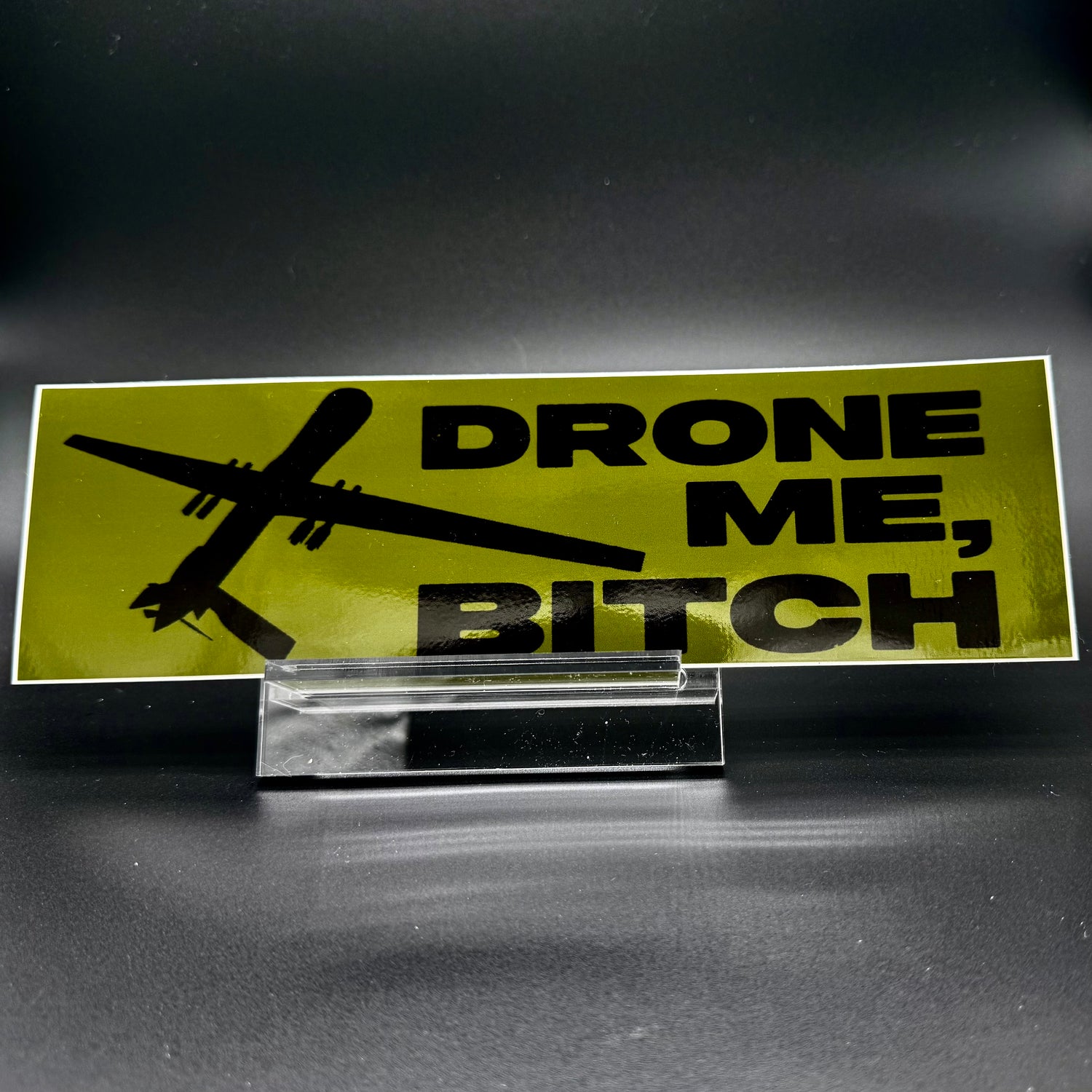 A bumper sticker in OD green with a reaper drone and the text
