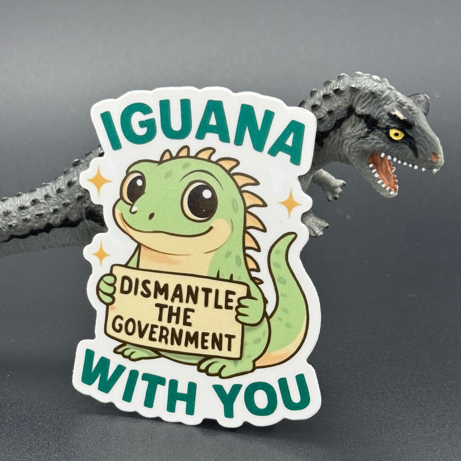Sticker of a Green Cartoon Iguana holding a sign saying