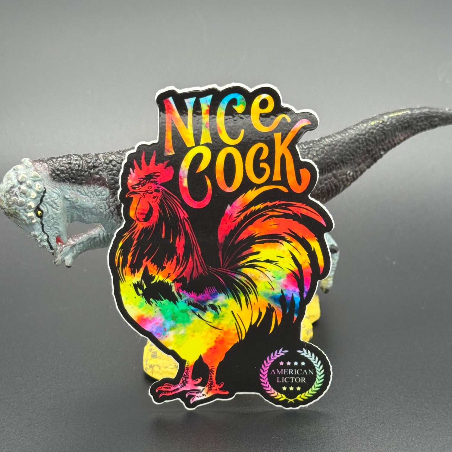 Sticker of a chromatic rooster on a black background with the text 'Nice Cock' posing with a dinosaur