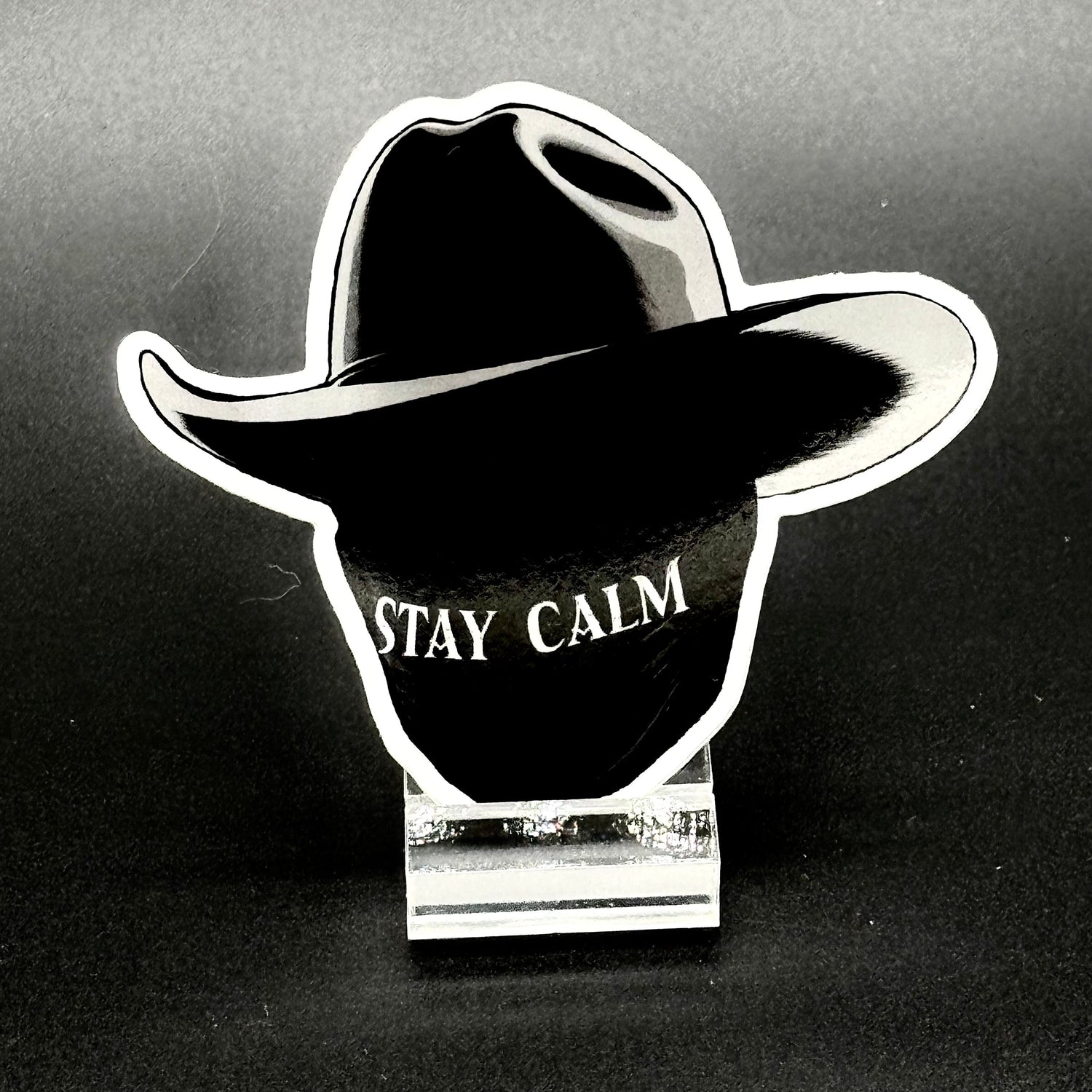 Sticker of a masked man with a black cowboy hat and the text 'Stay Calm'