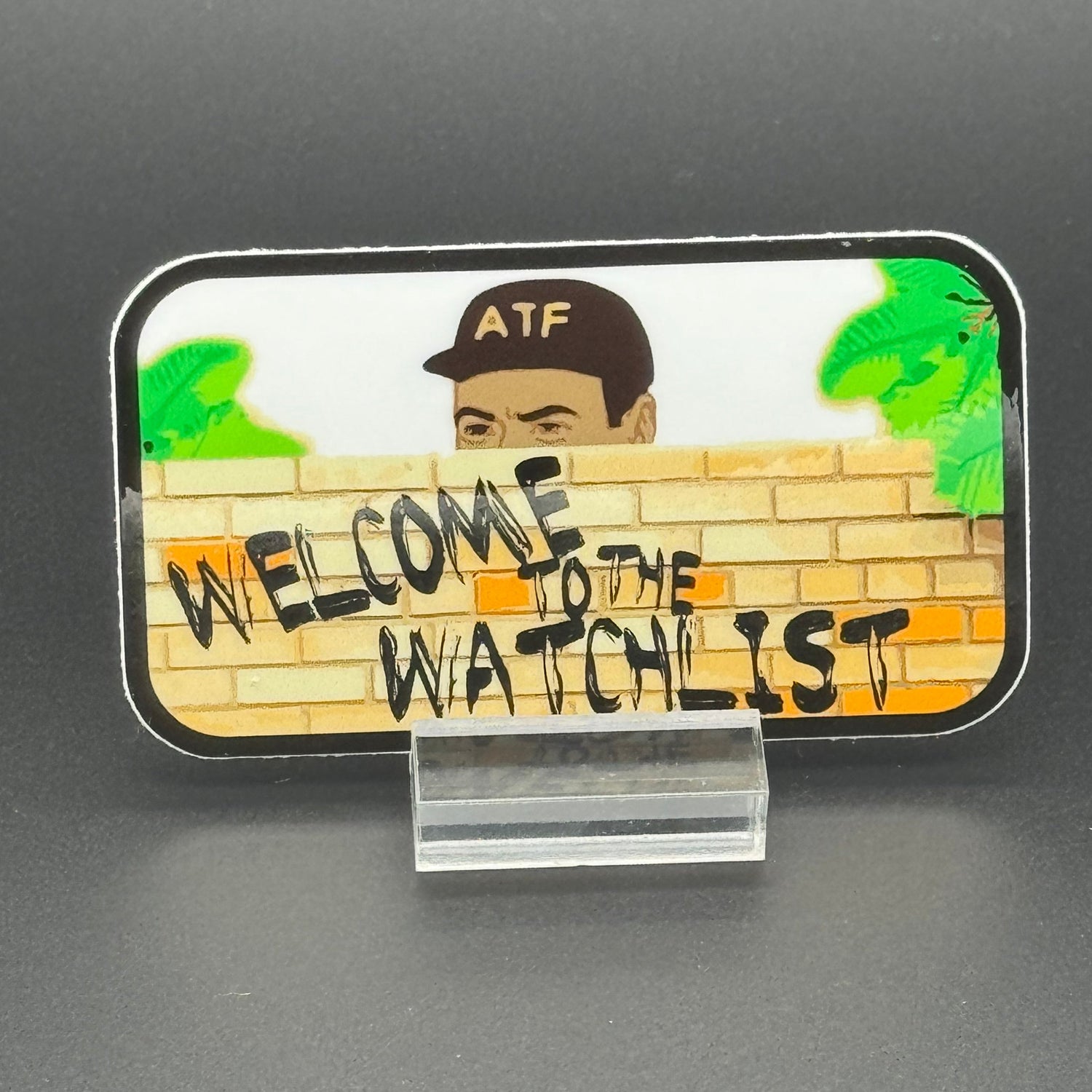 Sticker of an ATF agent peeking over a wall with the text 'Welcome to the Watchlist'