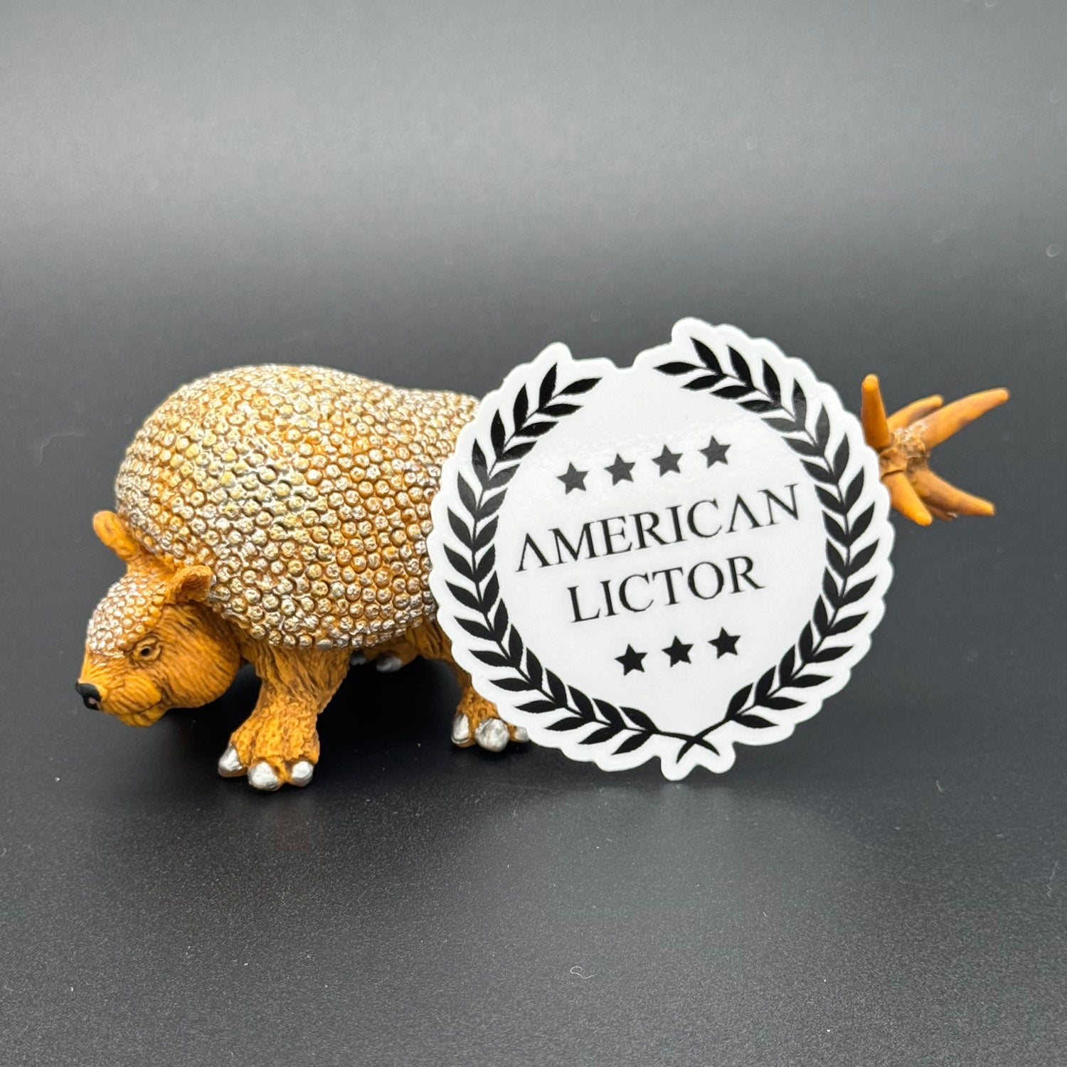 Sticker of the American Lictor Logo in white posing with a prehistoric mammal