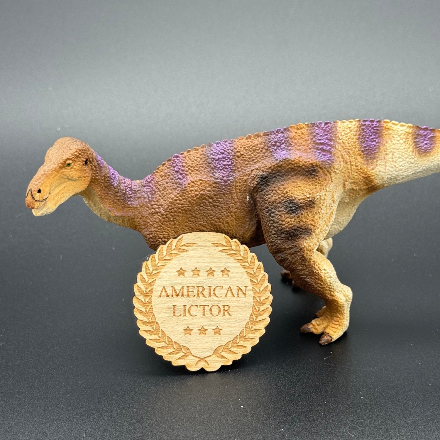Wood Sticker of the American Lictor Logo posing with a dinosaur