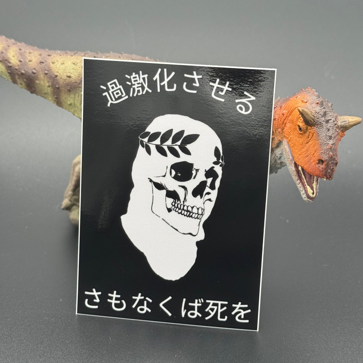 Sticker of the American Lictor skull logo with the text 'Radicalize or Die' in Japanese posing with a dinosaur