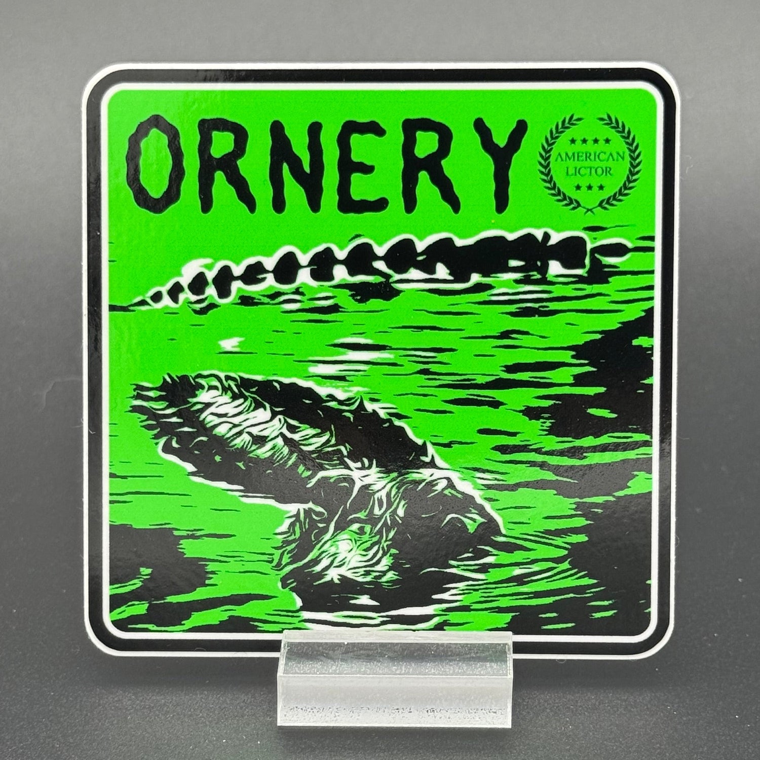 Black and green sticker of an alligator with the text 'Ornery'