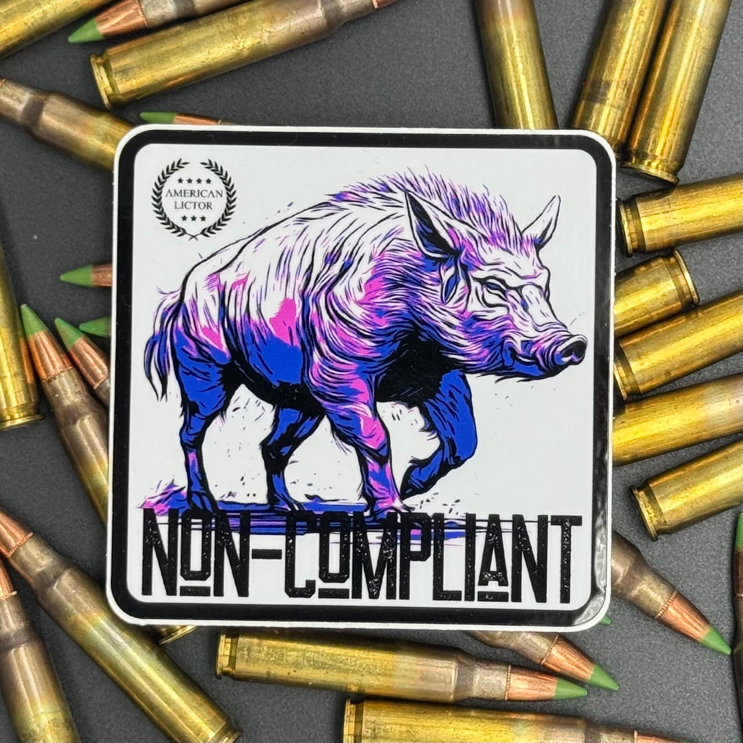 Black, purple, blue and white sticker of a boar with the text 'Non-Compliant' on a bed of ammo