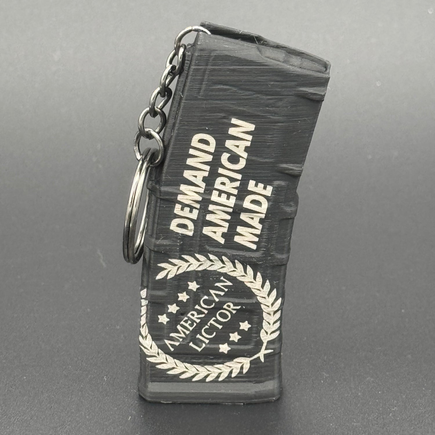 A black keychain shaped like an AR15 mag with the American Lictor logo and slogan Demand American Made'