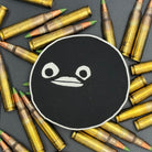 A leatherette patch of goofy cartoon character head wearing a ski mask on a bed of ammo