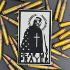 A white leatherette patch with a man with a skeleton mask draped in the American Flag with a Laurel Halo and cross and the text 'Hear my Prayer' on a bed of ammo