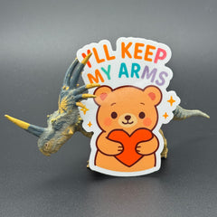 Sticker of a Brown Cartoon bear holding a heart saying "I'll keep my arms" posing with a dinosaur