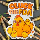 Sticker of a cute chicken with chicks saying "Cluck the FDA" on a bed of ammo