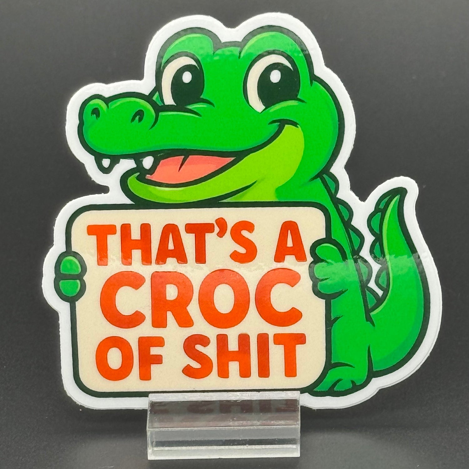Sticker of a Green Cartoon Crocodile holding a sign saying 