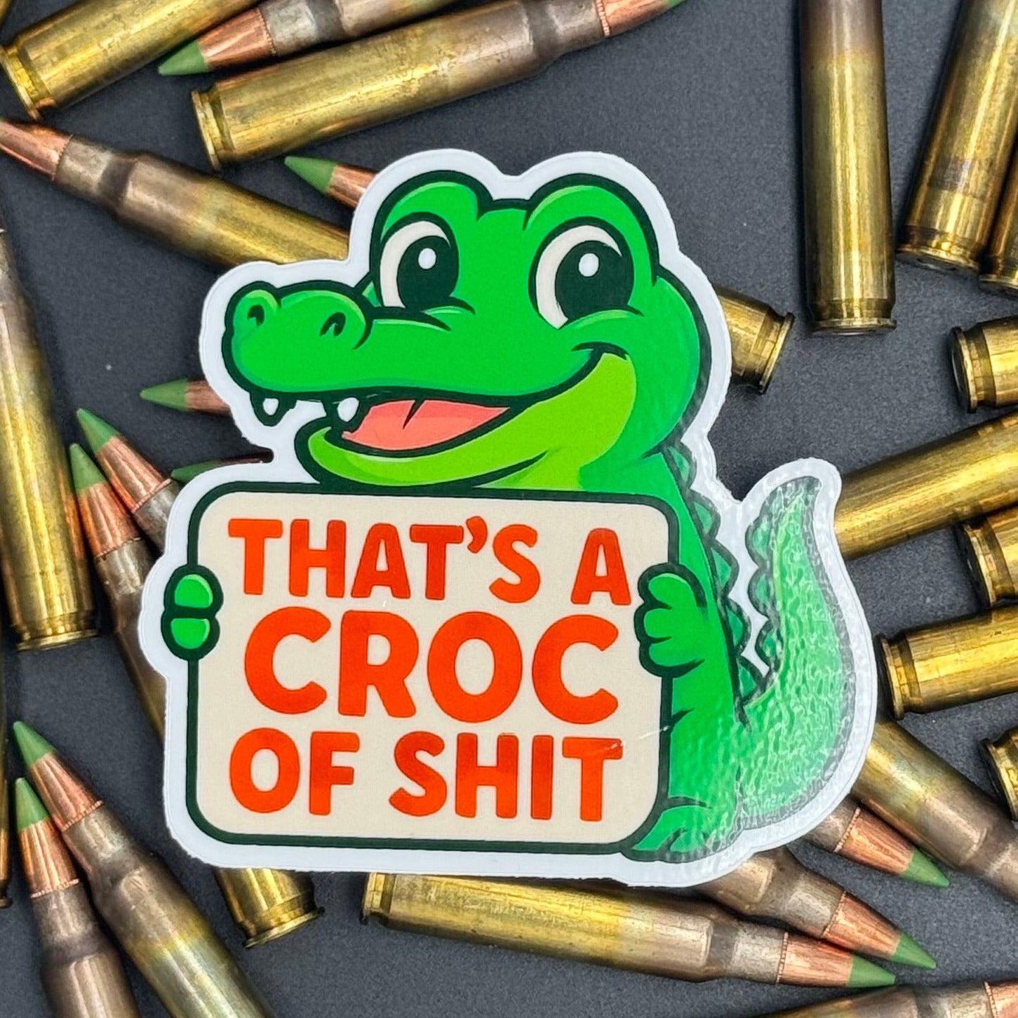 Sticker of a Green Cartoon Crocodile holding a sign saying 