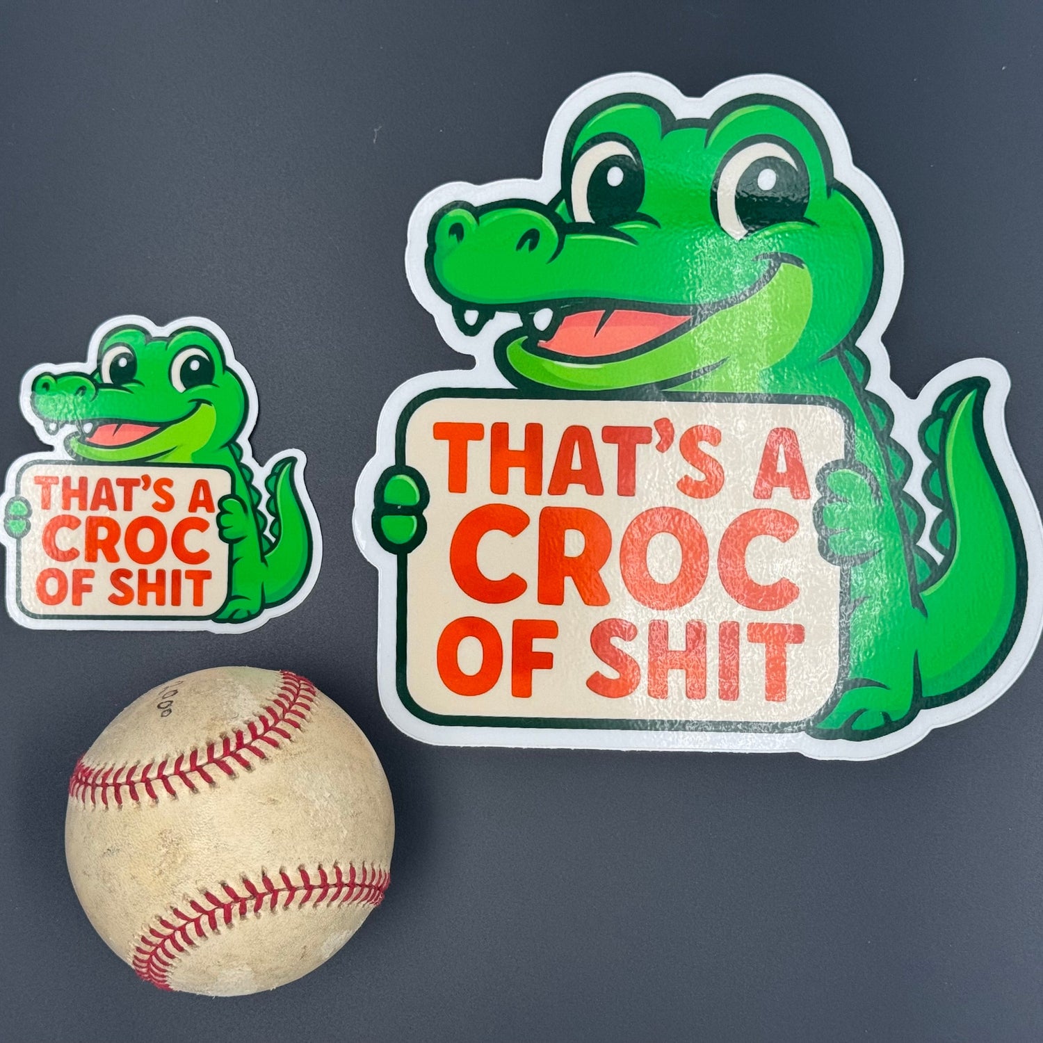 A small and Large Sticker of a Green Cartoon Crocodile holding a sign saying 