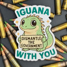 Sticker of a Green Cartoon Iguana holding a sign saying "Iguana dismantle the government with you" on a bed of ammo