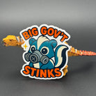 Sticker of a cute skunk in a gas mask saying "Big government stinks" posing with a dinosaur