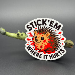 Sticker of a cute porcupine covered in blood saying "Stick 'em where it hurts" posing with a dinosaur