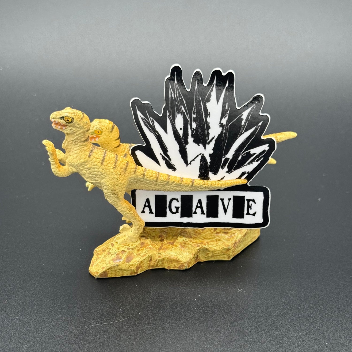 Sticker of Agave Logo in black and white posing with a dinosaur