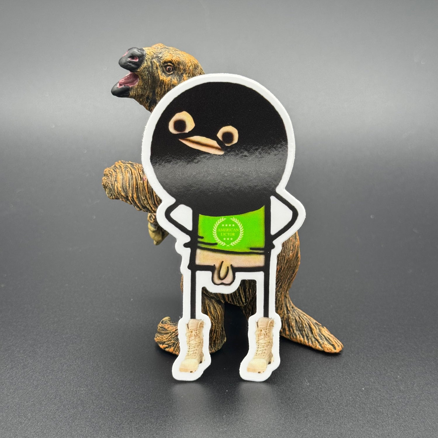 Sticker of a cartoon character wearing a ski mask with no pants on posing with a prehistoric mammal