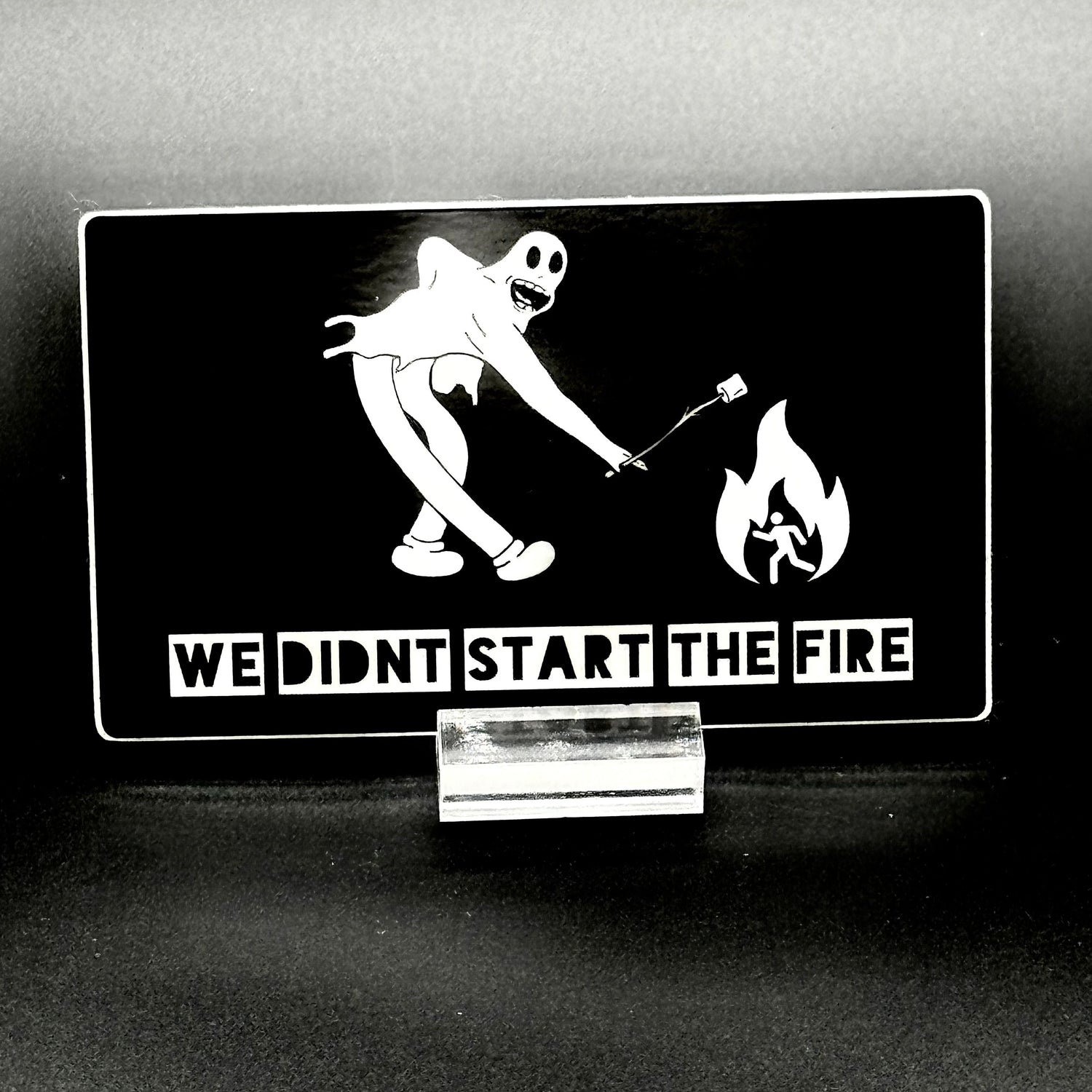 Sticker of a cartoon character in a ghost suit roasting a marshmallow over a fire
