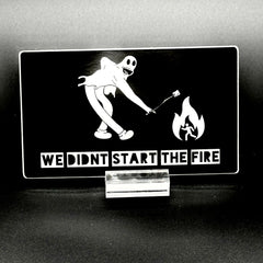 Sticker of a cartoon character in a ghost suit roasting a marshmallow over a fire