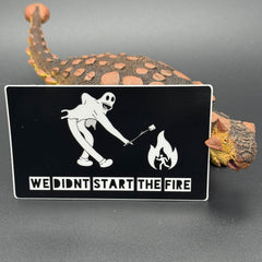 Sticker of a cartoon character in a ghost suit roasting a marshmallow over a fire posing with a dinosaur
