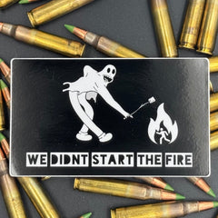 Sticker of a cartoon character in a ghost suit roasting a marshmallow over a fire on a bed of ammo