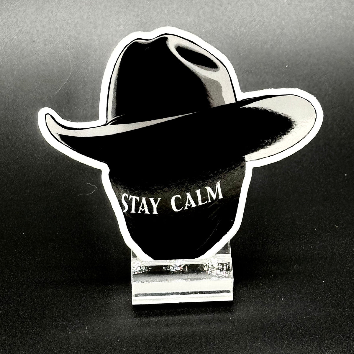 Sticker of a masked man with a black cowboy hat and the text 'Stay Calm'