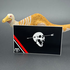 Sticker of a modern pirate flag with a skull with open mouth and arrow through the head and an upside down crown posing with a dinosaur