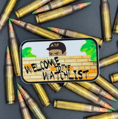Sticker of an ATF agent peeking over a wall with the text 'Welcome to the Watchlist' on a bed of ammo
