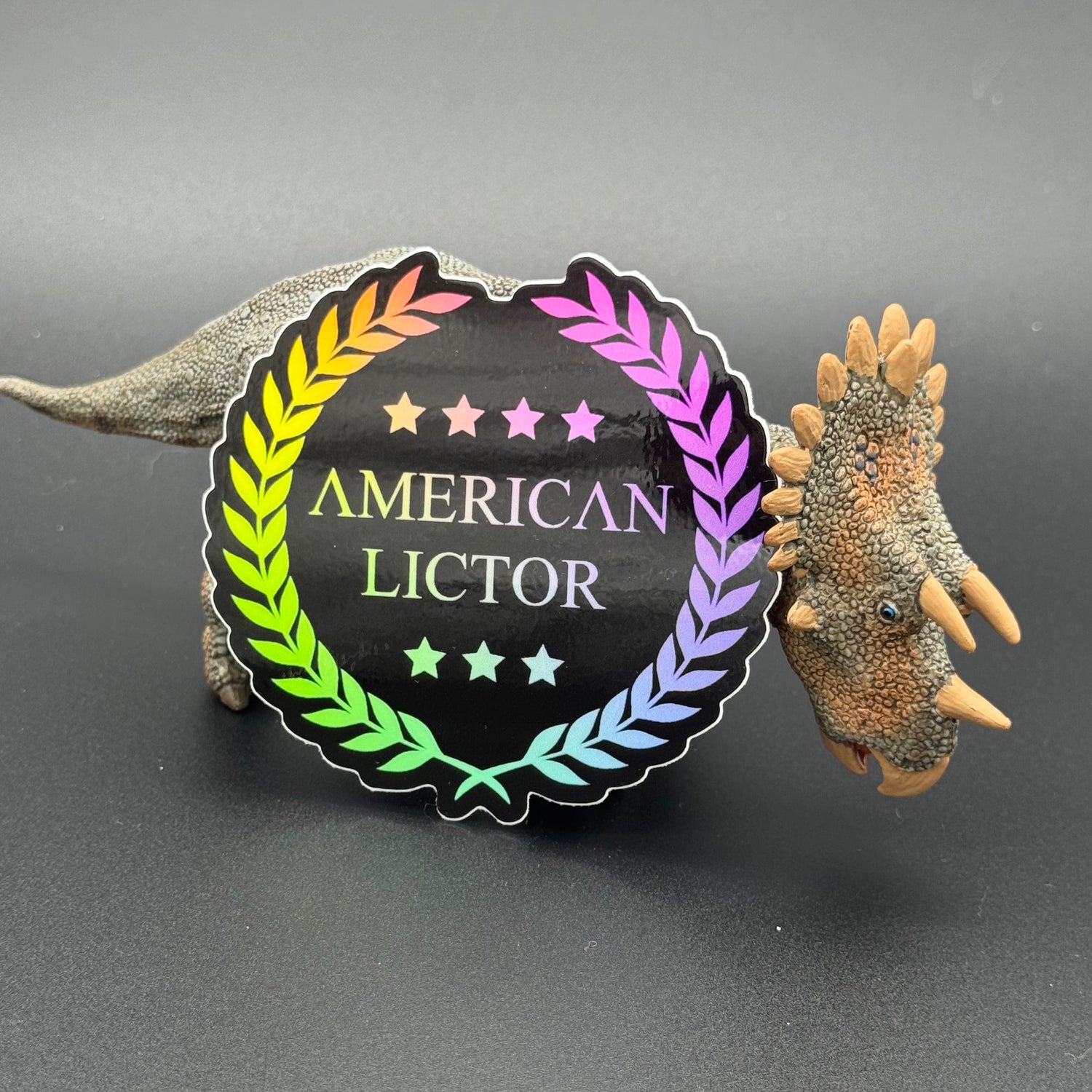 Sticker of the American Lictor Logo in black with chromatic coloring posing with a dinosaur
