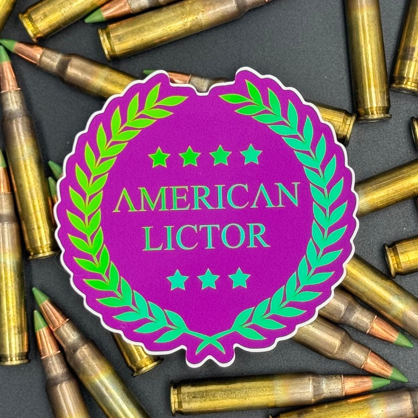 Sticker of the American Lictor Logo in Purple with green chromatic coloring on a bed of ammo