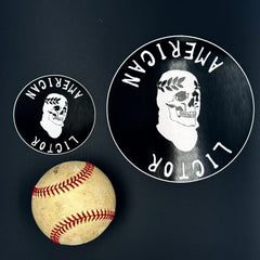 A small and large Sticker of the American Lictor Skull Logo in black pictured with a baseball for scale