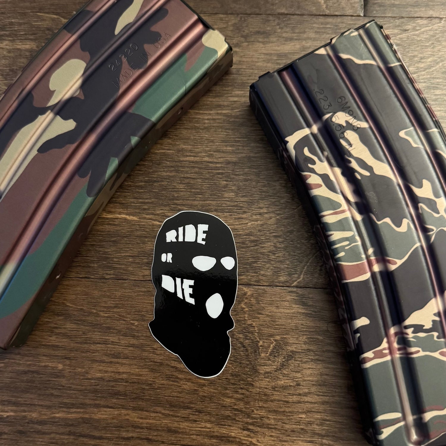 Camouflage magazines on a wooden surface with a 'Ride or Die' sticker.