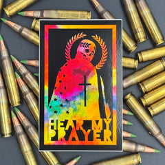 Chromatic sticker of a man draped in the American Flag with the text 'Hear my Prayer' on a bed of ammo