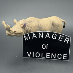 Black sticker with the text 'Manager of Violence' posing with a prehistoric mammal