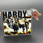 Black, yellow and white sticker of a Bison with the text 'Hardy' posed with a dinosaur