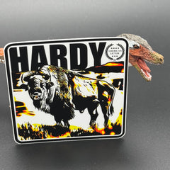 Black, yellow and white sticker of a Bison with the text 'Hardy' posed with a dinosaur