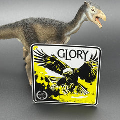 Black, yellow and white sticker of an eagle with the text 'Glory' posed with a dinosaur