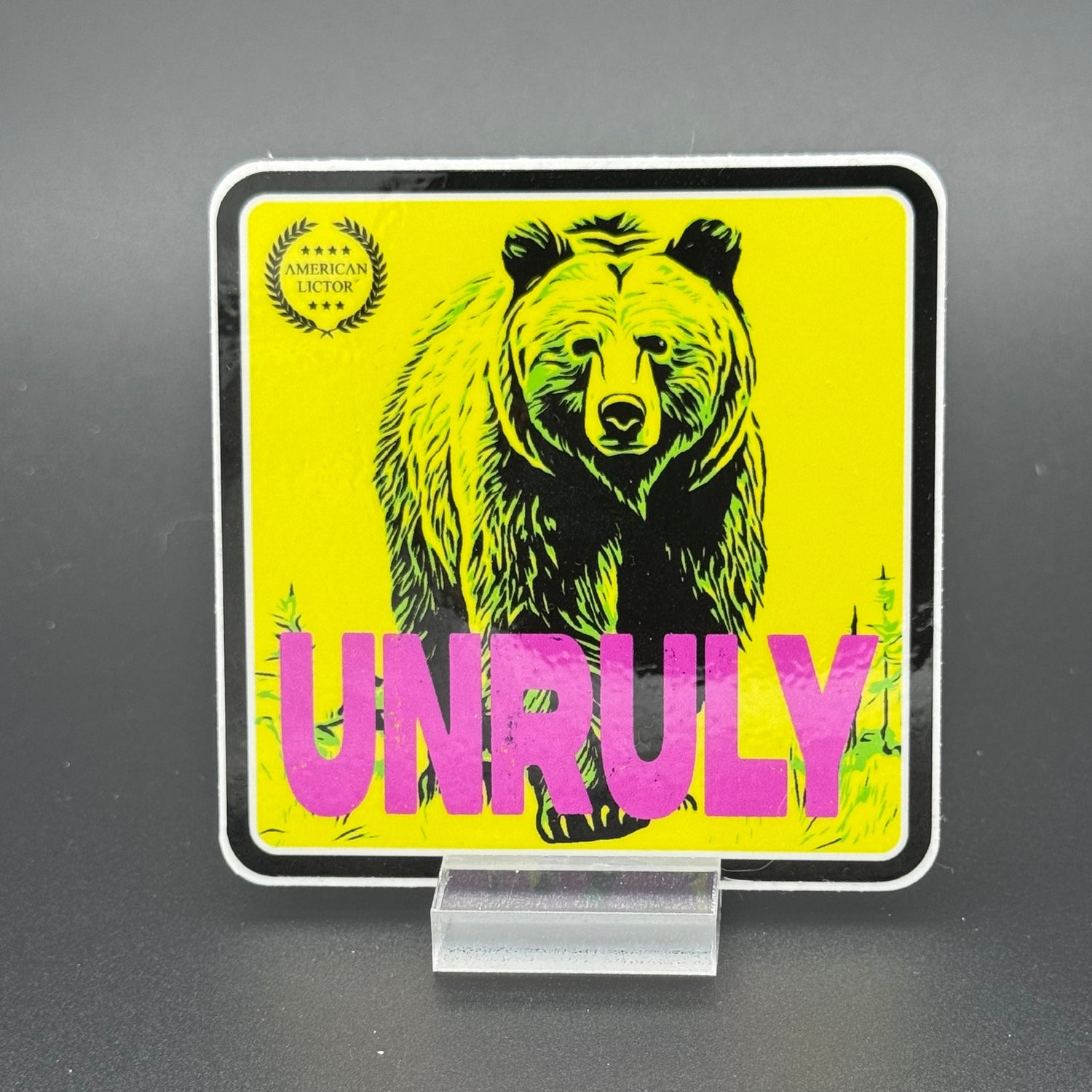 Yellow and pink Sticker of a grizzly bear with the text 'Unruly'