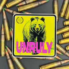Yellow and pink Sticker of a grizzly bear with the text 'Unruly' on a bed of ammo