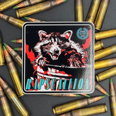 Black, red and teal Sticker of a Raccoon with the text 'Rapscallion' on a bed of ammo